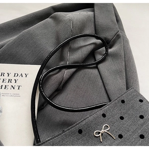 Détail du sac seau en tweed gris avec pois noirs et boucle en forme de nœud argenté