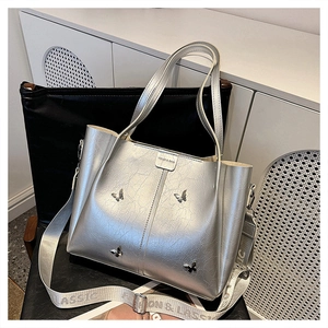 Detail of silver tote bag with butterfly metallic studs and wide fabric shoulder strap