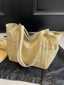 Minimalist beige large capacity canvas tote bag with dual zipper pockets on black surface
