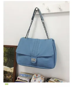 Détail du sac à bandoulière en denim bleu clair avec coutures et fermoir rotatif argenté