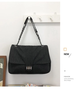 Détail du sac bandoulière en denim noir avec fermoir rotatif argenté et chaîne