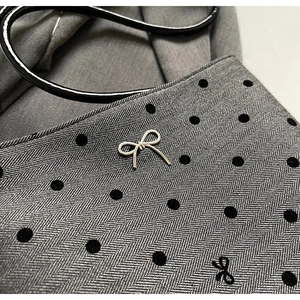 Détail du sac en tissu à chevrons gris avec pois noirs et ornement de nœud argenté