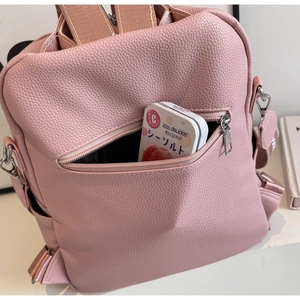 Détail de la poche zippée avant pratique sur un sac à dos en cuir rose à grain litchi