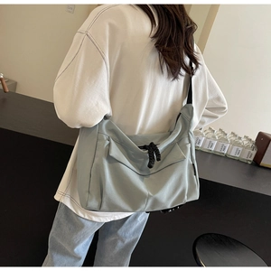 Lifestyle view of a light blue large capacity tote bag shown on model with casual white hoodie