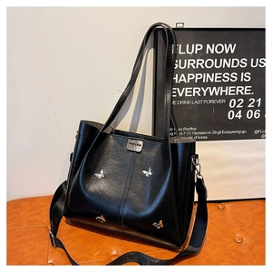 Detail of black vintage leather tote bag with silver butterfly hardware and wide strap