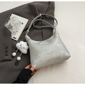 Minimalist silver PU leather shoulder bag with plush cloud charm on grey blazer