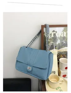 Détail de la texture denim bleue du sac cabas avec chaîne argentée et fermoir rotatif