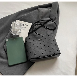 Détail du sac seau gris à pois avec nœud en métal argenté et bandoulière noire