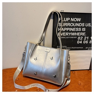 Detail of silver tote bag with metallic butterfly accents and retro textured finish