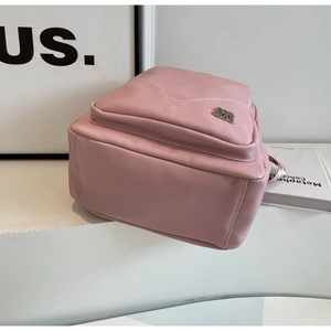 Détail de la texture cuir litchi rose et du logo M en métal sur le sac à dos chic