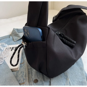 Détail du sac bandoulière en nylon noir avec poche latérale pour smartphone et cordon élastique