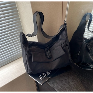 Detail view of large black canvas bag with rope zipper pull and utility pockets
