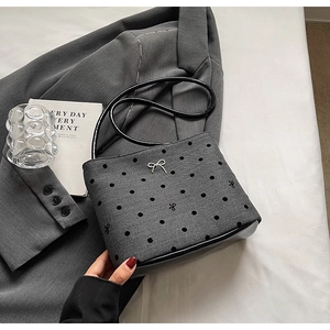 Gros plan sur le sac gris à pois avec un nœud argenté et une base en cuir noir élégant