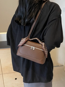 Brown lychee leather crossbody bag with silk scarf handle detail worn by model