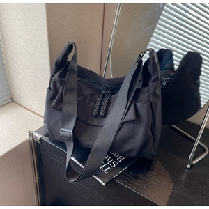Detail of black canvas dumpling bag featuring double zippers with woven knot pullers