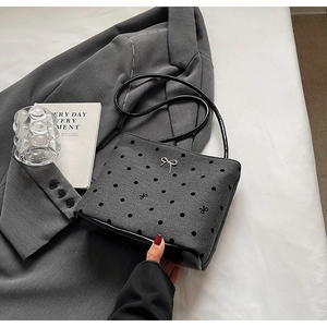 Détail du sac seau en toile grise à pois avec nœud et bandoulière en cuir