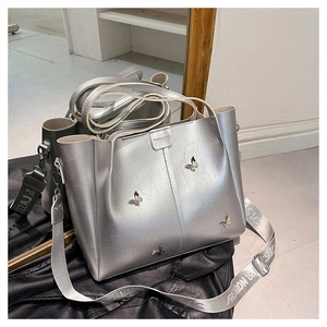 Detail of silver metallic tote bag with butterfly charms and fashion text shoulder strap