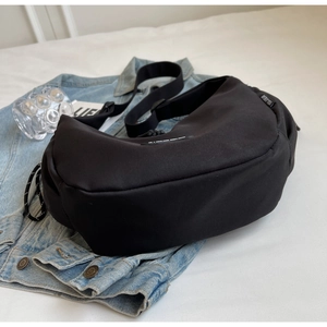 Détail du sac croissant en nylon noir avec étiquette tissée sur une veste en jean