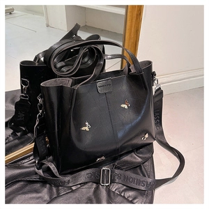 Detailed mirror view of black PU leather tote with silver butterfly and wide strap