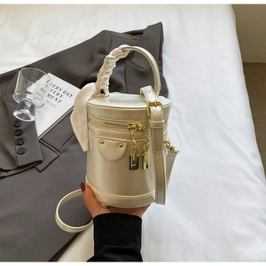 Detail of cream bucket bag featuring silk scarf handle and golden metal lock hardware