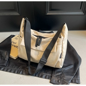 Detail of canvas commuter bag featuring black woven rope zipper pull and adjustable strap