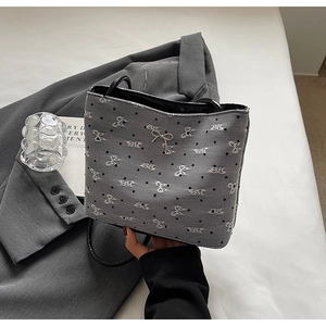 Détail du sac seau gris avec broderies de nœuds blancs et motifs à pois noirs