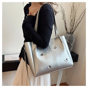 Detail of silver tote bag with metallic butterfly accent and adjustable strap