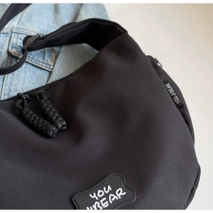 Détail du sac bandoulière en toile noire avec patch YOU BEAR et fermeture éclair robuste