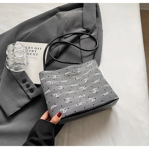 Détail du sac seau en toile grise avec imprimé papillon et nœud en métal argenté