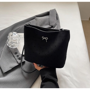 Détail du sac seau en jacquard noir avec noeud métallique sur une veste grise