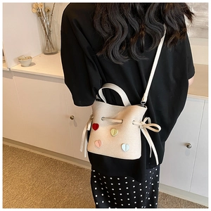 Sac seau beige avec patchs cœurs colorés porté par un modèle pour la taille