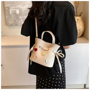 Détail d'un sac seau beige avec des patchs cœurs colorés et une fermeture à cordon