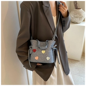 Détail du sac seau en denim bleu avec écussons cœurs colorés et bandoulière réglable