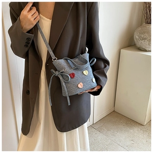 Détail du sac seau en tweed bleu clair avec patchs cœurs colorés en 3D et cordon