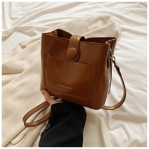 Détail d'un sac seau en cuir marron avec poche avant et anneaux de sangle métalliques