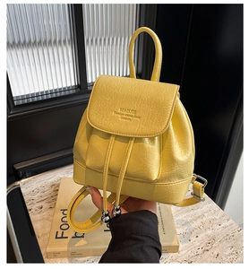 Detail of yellow leather backpack with flap drawstring closure and embossed logo