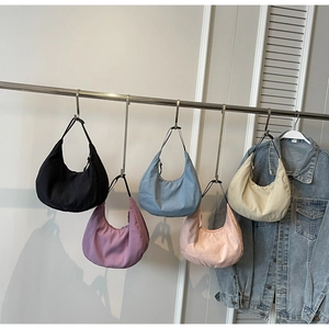 Selection of colorful nylon dumpling bags hanging on a rack with a denim jacket