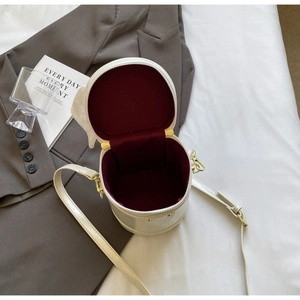 Detailed view of white cylindrical mini bag with burgundy velvet lining and gold zipper