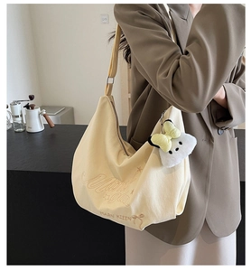 Dettaglio borsa beige in tela con ricamo a stella e ciondolo di peluche con fiocco giallo