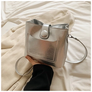 Détail du sac seau argenté texturé avec gravure de mode et fermeture par bouton-pression