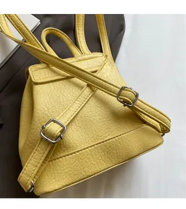 Detailed view of yellow backpack featuring litchi texture and adjustable shoulder straps