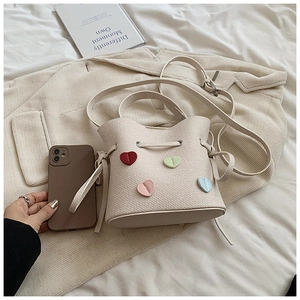 Détails d'un sac seau crème avec écussons cœurs 3D colorés et fermeture à cordon coulissant
