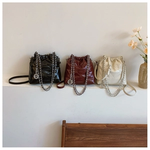 Three bucket bags in black, burgundy, and beige with diamond quilting and chain straps