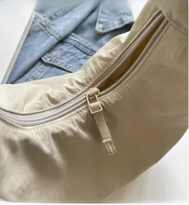 Close-up of smooth nylon zipper closure on beige crossbody bag with yellow lining