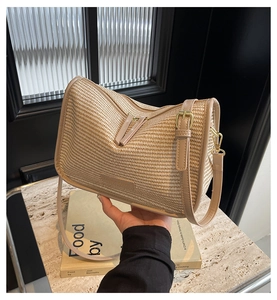 Close-up of woven straw handbag featuring premium leather straps and gold-tone hardware