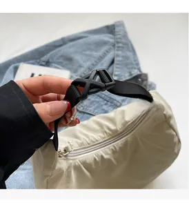 Detail of the durable plastic buckle and black nylon strap on the beige dumpling bag