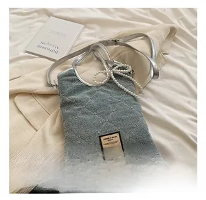 Détail du sac vintage en denim gris avec matelassage diamant, strass et perles d'ornement