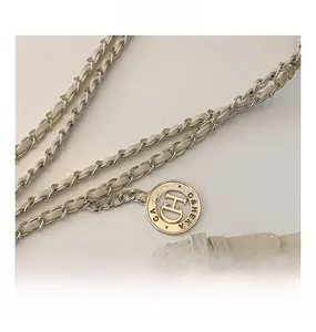 Detail of cream leather and silver chain strap with round engraved metal hardware
