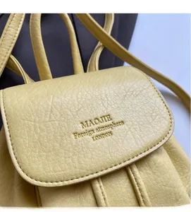 Detail of yellow pebbled leather backpack with embossed text and soft thin shoulder strap