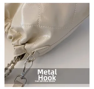 Detail shot of hardware hook and silver chain on a beige quilted leather bucket bag